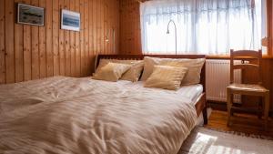 - une chambre dotée d'un grand lit avec des draps blancs et une fenêtre dans l'établissement Bellevue Aschberg, à Klingenthal