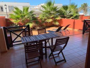 a table and chairs on a balcony with palm trees at Casa Achille in Cotillo
