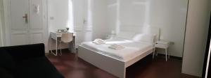 a white bedroom with a white bed and a table at Cagliari d'Amare Via Roma in Cagliari