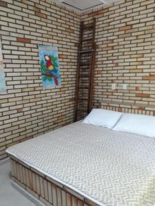 Cama en habitación con pared de ladrillo en Casa de Pedra - 14 pessoas - Bombinhas IMB2, en Bombinhas