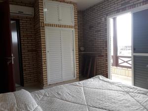 1 dormitorio con pared de ladrillo, cama y ventana en Casa de Pedra - 14 pessoas - Bombinhas IMB2, en Bombinhas