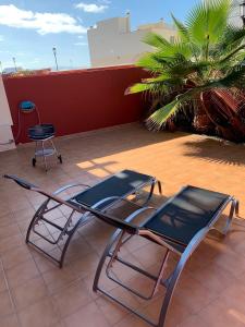 a lounge chair on a patio with a palm tree at Casa Achille in Cotillo