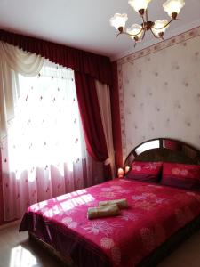 a bedroom with a bed with a red bedspread and a window at Pālena apartamenti in Tērvete