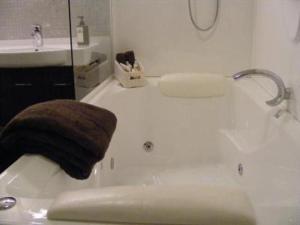 a bathroom with a bath tub with a brown towel at Terra Vive Suites & Apartments in Christchurch