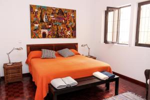 Vila Mira Mar في منديلو: غرفة نوم مع سرير وبطانية برتقالية