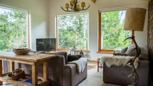 - un salon avec un canapé, une table et des fenêtres dans l'établissement Quinto Elemento Bariloche, à San Carlos de Bariloche