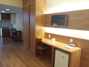 ein Hotelzimmer mit einem Schreibtisch und einem Fernseher an der Wand in der Unterkunft Mirante Flat in Ouro Branco