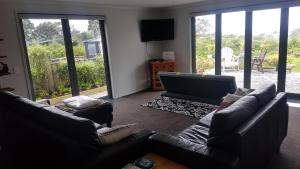 sala de estar con 2 sofás y TV de pantalla plana en Purakau Bed & Breakfast, en New Plymouth