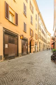 a cobblestone street in a city with buildings at Mercanzia Apartment, Palazzo Storico sotto le Due Torri in Bologna