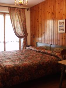 a bedroom with a bed and a large window at Hotel Garni St. Hubertus in Madonna di Campiglio