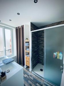 uma casa de banho com um chuveiro e uma porta de vidro em Gîte « La Vague » 8-10 pers em Grandcamp-Maisy