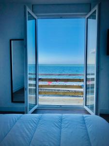 um quarto com vista para a praia a partir de uma janela em Gîte « La Vague » 8-10 pers em Grandcamp-Maisy