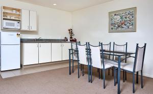 a kitchen with a table and chairs and a refrigerator at Barringtons Motor Lodge in Whakatane