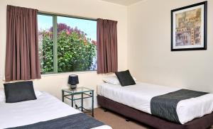 two beds in a room with a window at Barringtons Motor Lodge in Whakatane