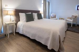 a bedroom with a large white bed and a chair at Portas da Villa in Miranda do Douro