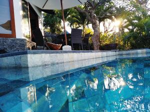a swimming pool with an umbrella next to a house at Villa Mimpi Manis infinity pool&180°Ocean view in Amed