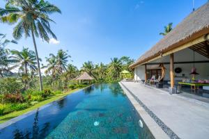an infinity pool in a resort with palm trees at Villa Themma Jungle - Sumptuous 3BR Luxury Villa with Majestic Jungle View North of Ubud in Ubud