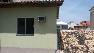 una casa verde con ventana y techo en Quitinete Cabo Frio, en Cabo Frío