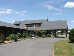 a large building with a driveway in front of it at Cedarwood Lakeside Motel & Conference Venue in Rotorua