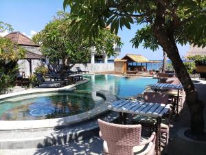 una piscina en un complejo con sillas y mesa en Classic Beach Villas, en Amed