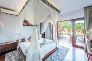 um quarto com uma cama de dossel e uma varanda em The Kasih Villas & Spa em Seminyak