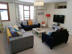 uma sala de estar com dois sofás e uma televisão em Shakespeare Cottage em Napier