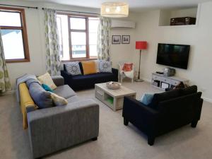 a living room with two couches and a tv at Shakespeare Cottage in Napier