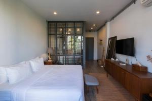 1 dormitorio con 1 cama blanca grande y TV de pantalla plana en Iron32 Hotel en Chiang Mai