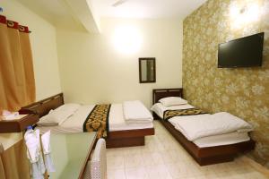 a hotel room with two beds and a flat screen tv at The Grand Hotel BD in Sylhet +23 photos