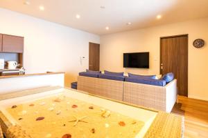 LAPIN MIHAMA Residence Hotel في شاتان: غرفة معيشة مع أريكة زرقاء وتلفزيون بشاشة مسطحة
