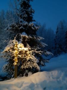 a sign in the snow next to a christmas tree at Villa Kaltio in Äkäslompolo