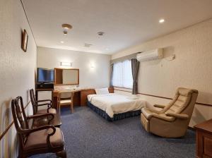a hotel room with a bed and a desk and chair at Crown Hotel Okinawa in Okinawa City
