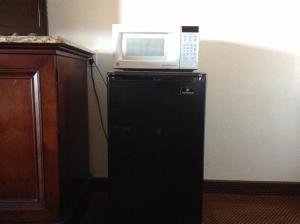 a microwave sitting on top of a black refrigerator at Heritage Inn Grand Prairie in Grand Prairie