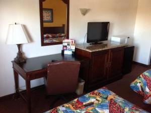 a hotel room with a desk with a television and a bed at Heritage Inn Grand Prairie in Grand Prairie