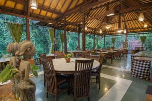 a dining room with tables and chairs and trees at Bali Spirit Hotel and Spa, Ubud in Ubud