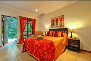 a bed room with a red bedspread and a large window at Amakoekoe Guest Lodge & Conference Venue in Johannesburg