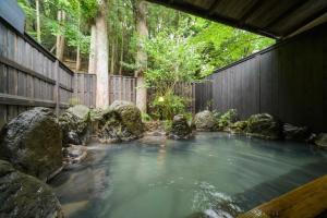 a pool of water with rocks and a wooden fence at Yufuin Hotel Mori-no-Terrace in Yufuin