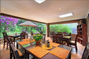 a dining room with tables and chairs and a large window at Amakoekoe Guest Lodge & Conference Venue in Johannesburg