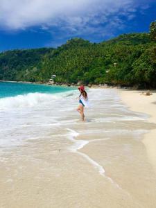 a woman is walking on the beach at CANIBAD SECRET PARADISE RESORT in Aumbay