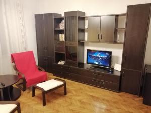 a living room with a tv and a red chair at Apartament Athenee Palace Bucharest in Bucharest