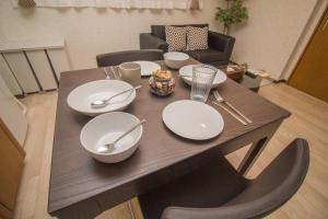 a wooden table with white plates and silverware on it at Nakayoshi Stay 401 in Osaka