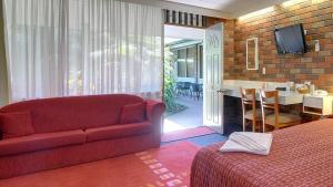 a living room with a red couch and a dining room at Cedar Lodge Motel in Morwell