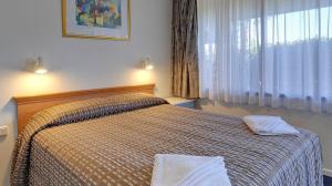 1 dormitorio con 1 cama con 2 toallas en Cedar Lodge Motel, en Morwell