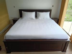 una cama grande con sábanas y almohadas blancas en Greenfield Bedz, en Hatton