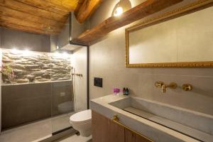 a bathroom with a sink and a toilet and a mirror at CAMARA SUITES in Andros