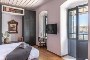 a bedroom with a bed and a desk and a tv at CAMARA SUITES in Andros