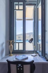 an office with a desk with a lamp and windows at CAMARA SUITES in Andros