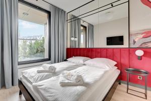 a bedroom with a large bed with a red headboard at Flamingo Beach Apartment in Gdańsk
