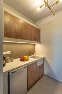a kitchen with wooden cabinets and a bowl of fruit on the counter at CAMARA SUITES in Andros