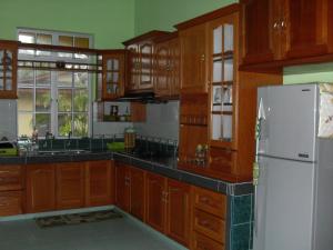 uma cozinha com armários de madeira e um frigorífico branco em Farah Banglo Homestay Kemasik em Kemasik